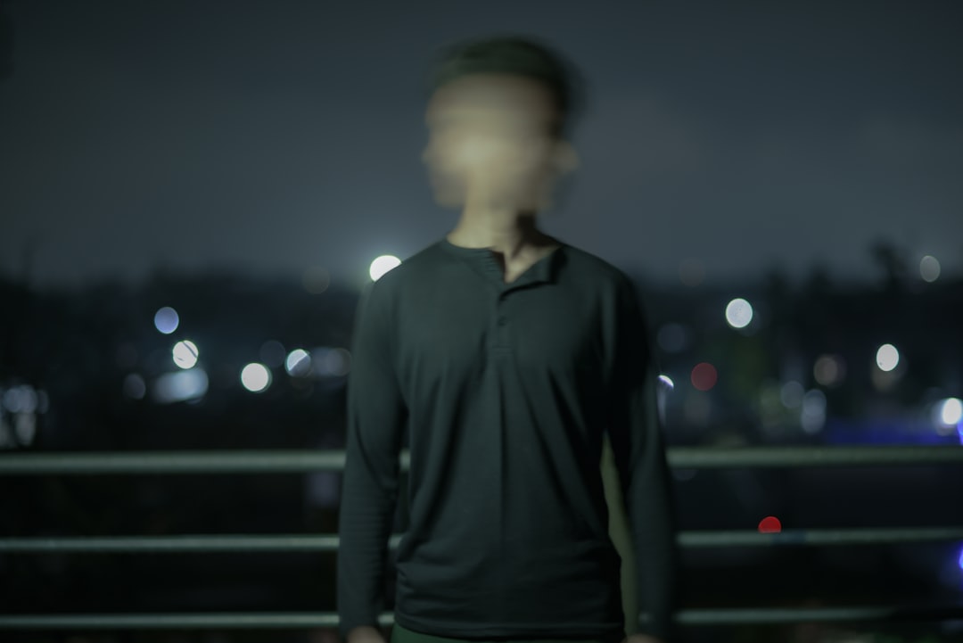 a man standing in front of a railing with lights in the background