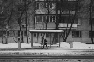 a man standing in front of a bus stop covered in snow